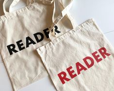 two totes bags with the words reader and reader printed on them, sitting next to each other