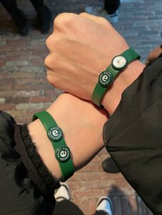 two people wearing green wristbands with starbucks logos on them, one is holding the other's hand