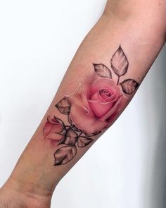 a woman's arm with a pink rose tattoo on the left side of her arm