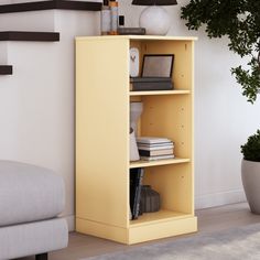 a yellow book shelf in the corner of a room with a couch and potted plant