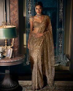 This antique gold saree features tonal sequin and bead embroidery. It is paired with fully embroidered matching blouse.From Seema Gujral's Kashish collection DELIVERY TIMEPlease allow 8-12 weeks for your outfit to arrive. FABRIC DETAILSNet Professional cleaning only. Modern Blouse Designs For Fancy Saree, Net Saree Look Modern, Stylish Sarees Party Wear, Modern Saree Party Wear, Gold Sequin Saree, Sequin Saree Party Wear, Saree Styles Modern, Sari Design, Sequin Saree