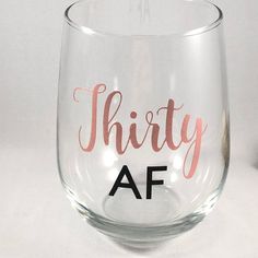 a wine glass with the word thirty af painted on it's side, sitting on a white surface