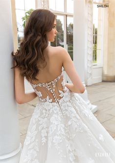 a woman in a wedding dress is leaning against a pillar with her back to the camera