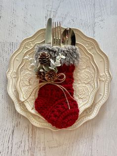 a white plate topped with a red stocking and a silverware holder filled with pine cones