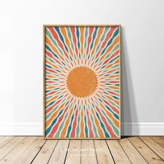 an orange sunburst on a white wall above a wooden floor