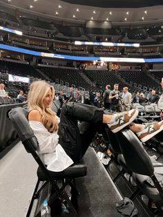 a woman sitting in a chair at a basketball game with her feet on the floor