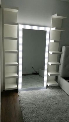 a large white mirror sitting in the middle of a room next to a book shelf