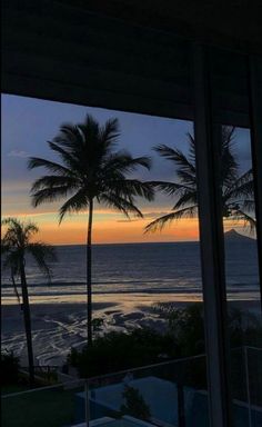 the sun is setting over the ocean and palm trees