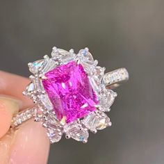 a close up of a person holding a ring with a pink and white diamond in it