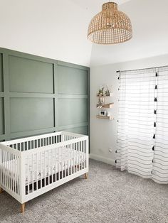 a baby's room with a crib in the corner and a lamp hanging from the ceiling