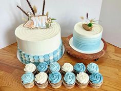 two cakes and cupcakes on a table with blue frosted icing decorations