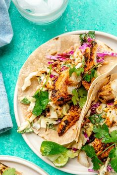 two fish tacos with cole slaw and cilantro on a white plate