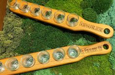 two wooden spoons with glasses in them sitting on green moss covered ground next to each other