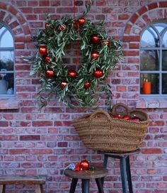 an olive wreath hanging from the side of a brick wall next to two stools