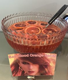 a glass bowl filled with liquid and oranges on top of a table next to a magazine