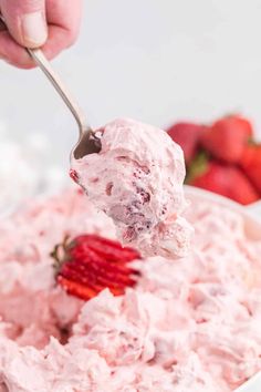 a spoonful of strawberry fluff is being lifted from a bowl with strawberries