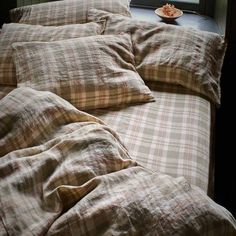 an unmade bed with two pillows and a plate of food on the table next to it