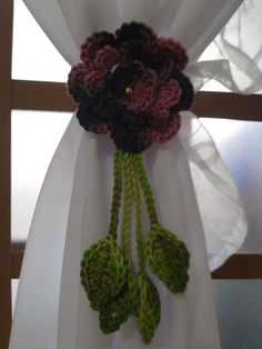 a white curtain with crocheted flowers hanging from it