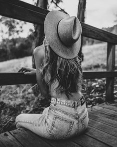 black and white photograph of a woman sitting on a wooden bench with her back to the camera