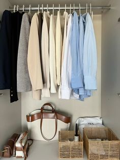 an organized closet with clothes hanging on the wall and baskets under it, along with shoes and purses