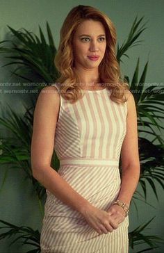 a woman standing in front of a potted plant wearing a white and beige striped dress