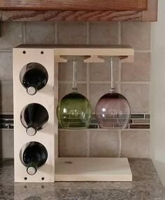 three wine glasses are sitting on a shelf in front of a counter top with a tile backsplash