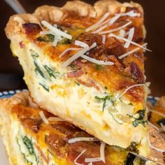 two slices of quiche with cheese and spinach on a blue and white plate