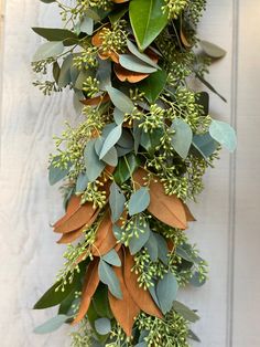 a bunch of green and orange leaves hanging from the side of a building