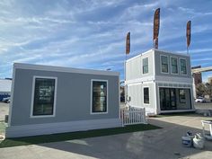 two tiny houses sitting next to each other on top of a parking lot in front of a building