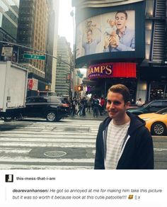 a man standing in the middle of a cross walk with cars and people on it