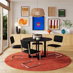 a dining room table with four chairs in front of an art work on the wall