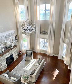 an aerial view of a living room with couches, fireplace and chandelier