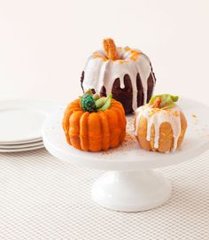 two bundt cakes sitting on top of a white cake plate next to each other