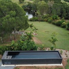 an aerial view of a pool in the middle of a lush green field with trees