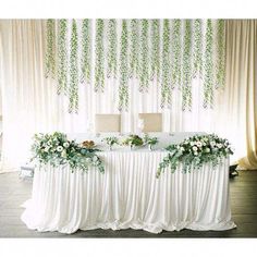 the table is covered with white flowers and greenery