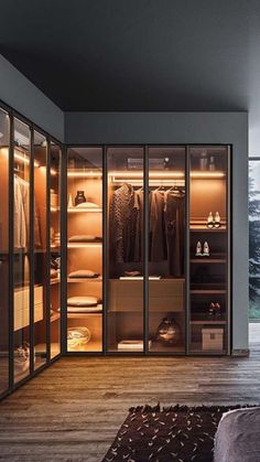 a walk - in closet with glass doors and lots of clothes hanging on the shelves