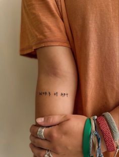 a woman's arm with the words work of art tattooed on her left arm