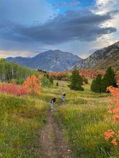 two people walking down a trail in the mountains