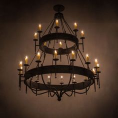 a chandelier with many lit candles hanging from it's centerpiece in a dark room