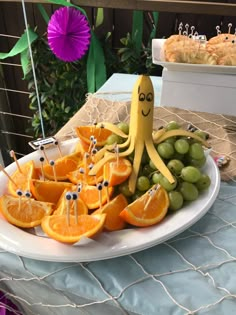 an octopus made out of oranges and grapes on a plate