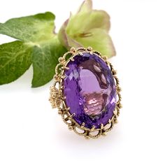 Featured here is the most spectacular 14 karat yellow gold floral crown ring that is showcasing a 52 carat faceted oval amethyst stone. Enough brilliance suited for a Queen! This ring is one of a kind and a size 8-8.5. -Details- • Materials : 14 karat solid gold and a faceted amethyst. • Measurements : face of ring 36 mm x 29 mm, carat weight of stone: 52 carats, ring size: 8-8.5.• Handmade on Martha's Vineyard. Please familiarize yourself with my policies before purchasing from my shop https:// Formal Heirloom Amethyst Cabochon Ring, Formal Oval Cabochon Amethyst Ring, Elegant Yellow Gold Amethyst Cabochon Ring, Elegant Yellow Gold Cabochon Amethyst Ring, Heirloom Style Purple Oval Amethyst Ring, Elegant Purple Amethyst Ring Oval Cabochon, Elegant Oval Cabochon Amethyst Ring For Formal Occasions, Elegant Purple Oval Cabochon Amethyst Ring, Elegant Formal Amethyst Ring With Large Stone