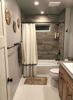 a bathroom with a toilet, sink and bathtub next to a wooden shower curtain