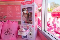 a pink candy vending machine sitting in front of a window