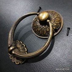 an antique brass door handle on a black leather surface