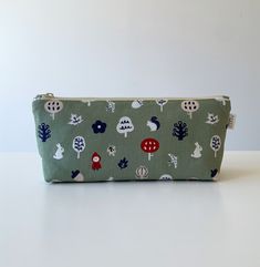 Cute cartoon nature fabric large capacity pencil case, pencil pouch, zipper bag, cosmetic bag, makeup bag Handmade in the UK Organize your essentials in style with this cute cartoon nature fabric large capacity pencil case. Featuring a playful cartoon design of trees and animals, this versatile zipper bag is perfect for storing pens, pencils, makeup, or other daily essentials. Handmade in the UK, this pencil pouch is both functional and charming, offering ample space for all your items while kee Green Pencil Shaped Case With Zipper Closure, Cute Green Zipper Pouch Pencil Case, Cute Green Pencil Case With Pen Holders, Green Pencil Case With Zipper Closure For Gift, Green Pencil Case With Zipper Closure As Gift, Cartoon Nature, Nature Fabric, Bag Makeup, Ykk Zipper