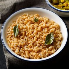 two bowls filled with rice and vegetables on top of a gray cloth next to each other