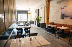 an empty restaurant with tables and chairs in front of a brick wall that has been painted white