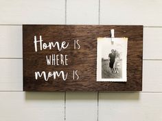 a wooden sign hanging on the side of a wall with a picture frame attached to it that says, home is where mom is