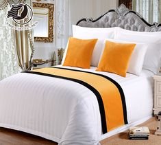 a white bed with orange and black pillows