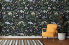 a yellow chair sitting on top of a wooden floor next to a wall covered in flowers